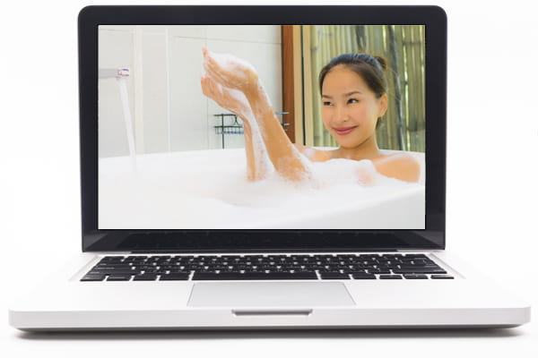 Laptop screen showing image of woman taking a bubble bath.