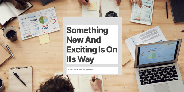 Screenshot of a custom coming soon page using an image of laptops and paperwork planning on a desk